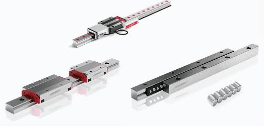 Schneeberger to globalny dostawca technologii ruchu liniowego i wysokoprecyzyjnych systemów pozycjonowania, działający głównie w sektorze maszyn przemysłowych i automatyki. Wysokoprecyzyjne komponenty do ruchu liniowego (Linear Motion Components) firmy SCHNEEBERGER. Centralny element to szczegółowy widok prowadnicy profilowej (np. MONORAIL), wykonanej z hartowanej stali. Widoczna jest szyna oraz wózek jezdny z elementami tocznymi, zaprojektowane dla zapewnienia beztarciowego i precyzyjnego ruchu w maszynach. Kolory to głównie metaliczna szarość i srebro, symbolizujące przemysłową dokładność i jakość.