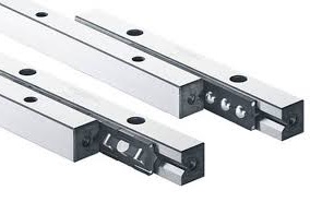 Prowadnice Liniowe Schneeberger Typ R i RD w DAKAM Obraz jest ucieleśnieniem inżynierskiej klasyki i modułowej wszechstronności. Prezentuje najpopularniejszy na świecie standard prowadnic liniowych &ndash; Typ R i RD marki Schneeberger. Kompozycja ukazuje je jako fundament budowy maszyn precyzyjnych, zestawiając surową elegancję szlifowanej stali z r&oacute;żnorodnością dostępnych koszyk&oacute;w. Całość osadzona jest w kontekście autoryzowanego polskiego dystrybutora DAKAM, co gwarantuje dostępność i oryginalność produkt&oacute;w. Dominują barwy: lustrzana stal, złoty mosiądz (koszyki) lub czerń i biel. Standard, kt&oacute;ry wyznacza jakość: W centrum uwagi, na czystym stole projektowym, znajduje się rozłożony zestaw prowadnic: &bull;	Szyny Typ R (Klasyk): Widoczne są dwie stalowe szyny o przekroju prostokątnym. Kluczowym elementem jest idealnie szlifowana bieżnia w kształcie litery "V" (90&deg;). Światło załamuje się na krawędziach, podkreślając precyzję wykonania. &bull;	Szyny Typ RD (Oszczędność miejsca): Obok lub w konfiguracji z R, widoczna szyna typu RD. Warto pokazać, że może ona pełnić funkcję elementu nośnego i mocującego jednocześnie (często posiada otwory gwintowane), co pozwala na bardziej zwarte konstrukcje. &bull;	Koszyki (Serce układu): Pomiędzy szynami wyeksponowane są r&oacute;żne typy koszyk&oacute;w, pokazując wszechstronność systemu: o	Koszyk wałeczkowy (Typ AC): Metalowy, solidny, do dużych obciążeń. o	Koszyk kulkowy (Typ AK): Do lżejszych, płynnych ruch&oacute;w. o	Koszyk z tworzywa: Dla cichej pracy. &bull;	Modułowość: Elementy są ułożone tak, aby sugerować, że można je dowolnie łączyć, tworząc prowadnicę o idealnej długości i parametrach. &bull;	Marka Premium: Na boku szyny widoczne jest wyraźne, grawerowane logo Schneeberger. Sprawdzony Polski Dystrybutor DAKAM: Tło buduje wizerunek solidnego partnera: &bull;	Rysunek Techniczny: W tle może być widoczny fragment projektu CAD, pokazujący zastosowanie szyn R/RD w stole krzyżowym. &bull;	Magazyn DAKAM: P&oacute;łki wypełnione charakterystycznymi opakowaniami Schneeberger świadczą o dużej dostępności magazynowej (r&oacute;żne długości i rozmiary). &bull;	Logo Dystrybutora: W dyskretnym, ale widocznym miejscu umieszczone jest logo DAKAM, z dopiskiem "Autoryzowany Dystrybutor Schneeberger". Obraz niesie jasny komunikat: "Szyny Schneeberger Typ R i RD to światowy standard w technice liniowej. W DAKAM oferujemy pełną gamę tych klasycznych prowadnic oraz pasujących koszyk&oacute;w wałeczkowych i kulkowych, dostępnych od ręki dla Twoich projekt&oacute;w".