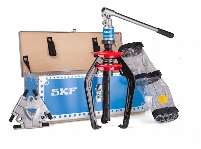 Zestaw SKF TMMA 75H SET. Ściągacz z płytą do odklejania w DAKAM. Kompletny Zestaw do Demontażu SKF TMMA 75H SET w DAKAM Obraz jest ucieleśnieniem wszechstronności i profesjonalnego przygotowania do każdego zadania serwisowego. Prezentuje nie tylko samo narzędzie, ale kompletny system (SET) zamknięty w jednej walizce, rozwiązujący problem demontażu łożysk nawet w trudno dostępnych miejscach. Kompozycja łączy techniczną elegancję uporządkowanego zestawu z logistyczną sprawnością autoryzowanego polskiego dystrybutora DAKAM. Dominują barwy: czarny mat (ściągacz), stal (płyty) oraz biel/błękit opakowań SKF. Mobilny warsztat w jednej walizce: W centrum uwagi, na czystym stole warsztatowym, znajduje się otwarta, solidna metalowa walizka z idealnie dopasowanymi wkładkami, prezentująca zawartość zestawu SKF TMMA 75H SET: • Ściągacz Hydrauliczny (TMMA 75H): Centralny element – znany z poprzednich ujęć ściągacz z zintegrowaną pompą i siłownikiem (75 kN). Jego obecność w zestawie gwarantuje siłę. • Płyta do Odklejania (Tri-section Pulling Plate): Kluczowy wyróżnik wersji "SET". Widoczna jest trójdzielna płyta (model TMMS 100), umieszczona w dedykowanym gnieździe lub zaprezentowana obok ściągacza. Jej ostre krawędzie wizualnie komunikują możliwość uchwycenia łożyska za pierścień wewnętrzny, tam gdzie zwykłe ramiona nie mają dostępu. To rozwiązanie problemu łożysk osadzonych "na płasko". • Przedłużki Ramion: Widoczne są stalowe przedłużki, które pozwalają zwiększyć zasięg narzędzia. • Koc Ochronny: Zwinięty w przegrodzie koc/siatka ochronna, podkreślający dbałość o BHP. • Porządek i Gotowość: Całość wygląda na idealnie zorganizowaną – każde narzędzie ma swoje miejsce, co sugeruje profesjonalizm serwisanta i brak ryzyka zgubienia elementów. Sprawdzony Polski Dystrybutor DAKAM: Tło jest subtelnie rozmyte (efekt bokeh), ale buduje zaufanie: • Magazyn DAKAM: W tle widać stos zamkniętych walizek SKF SET, gotowych do wysyłki. Potwierdza to, że DAKAM posiada te zaawansowane zestawy na stanie magazynowym. • Logo Dystrybutora: W dyskretnym, ale widocznym miejscu umieszczone jest logo DAKAM, z dopiskiem "Autoryzowany Dystrybutor Narzędzi SKF". Obraz niesie jasny komunikat: "W DAKAM kupisz nie tylko ściągacz, ale kompletne rozwiązanie. Zestaw SKF TMMA 75H SET zawiera hydrauliczny ściągacz EasyPull oraz trójdzielną płytę do odklejania, co pozwala na bezpieczny demontaż każdego łożyska, nawet tego przylegającego do oprawy".