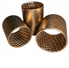 Opis obrazu: Fotografia produktowa przedstawia różnorodne tuleje ślizgowe z brązu, kluczowe komponenty w budowie maszyn i urządzeń. Na zdjęciu widoczne są zarówno tuleje z litego brązu (np. RG7), jak i tuleje ze spieków brązu, które różnią się wykończeniem powierzchni – od gładkiego połysku po matową, porowatą strukturę nasączoną olejem. Różnorodność kształtów, w tym tuleje proste (cylindryczne) oraz tuleje kołnierzowe, ilustruje szerokie możliwości zastosowania tych łożysk ślizgowych. Złocista barwa brązu świadczy o wysokiej zawartości miedzi, co przekłada się na doskonałe właściwości ślizgowe, odporność na korozję i wysoką nośność. Jest to idealny wybór do aplikacji wymagających niezawodności w trudnych warunkach pracy.